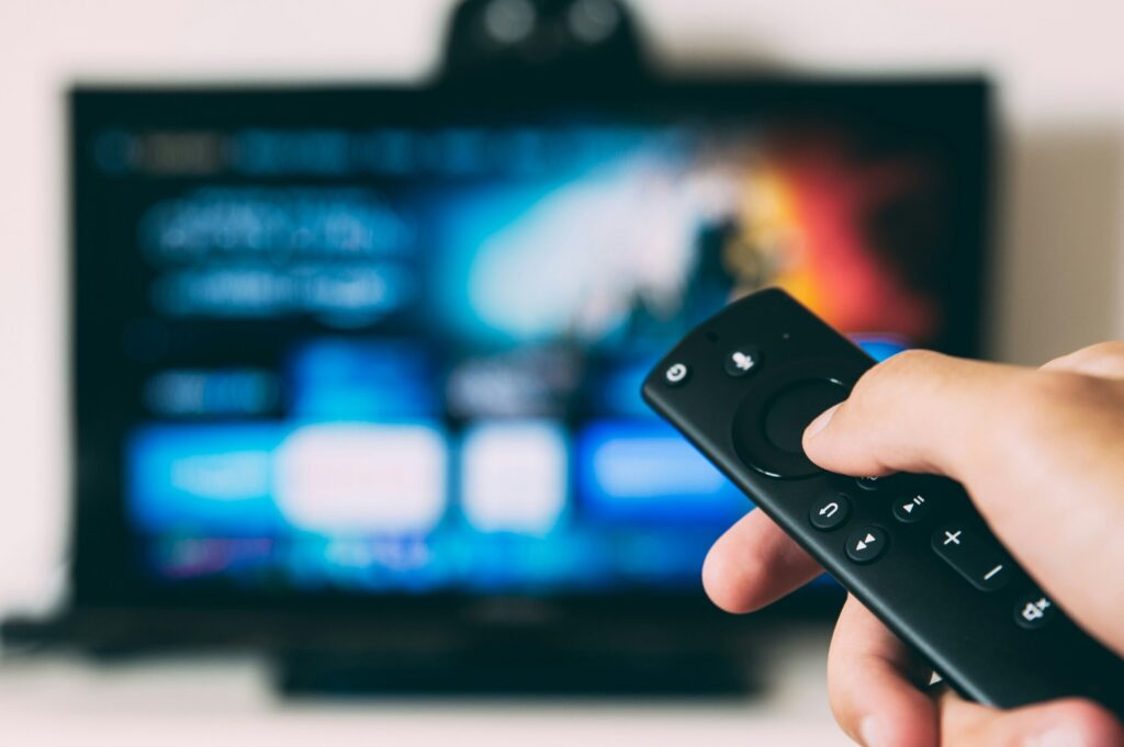 テレビ画面に向けてリモコンを構える手元のアップ